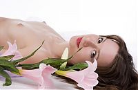 Babes: young curly brunette girl with a pink flower posing in blue textiles