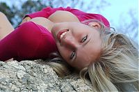 Babes: cute young blonde girl posing on rocks in a tight pink sweater