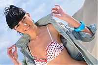 Babes: young black haired girl with a straight fringe undresses herself on the sand