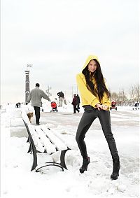 Babes: young brunette girl undresses a yellow coat and black leather pants outdoors in the winter