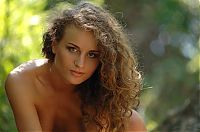 Babes: young curly brunette girl naked on rocks in the forest