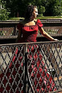 Nake.Me search results: young curly brunette girl reveals in a red dress at the stone building entrance