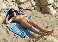 Nake.Me search results: young brunette girl sunbathing with sunglasses on the beach with a towel in the sand