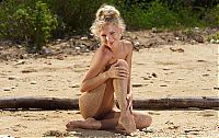 Babes: young blonde girl posing on the sandy beach with driftwood and remains of trees