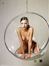 Babes: young brunette girl posing in a transparent vitreous glass swing chair