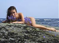 Babes: young brunette girl posing on tree roots at the bank of the sea on the rocky coast