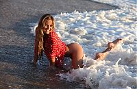 Babes: young blonde girl reveals her red blouse with white dots on the beach at the sea