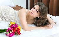 Babes: young brunette girl with long hair reveals her white negligee in the bed with flowers