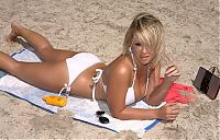 blonde girl with natural breasts reveals her tanned body and white bikini on the beach at the sea