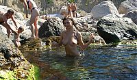 Nake.Me search results: young brunette girl naturist undresses her sport undershirt and blue shorts in the sea on the public rocky beach