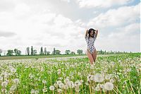 Babes: young black haired girl undresses her bodysuit on the field of dandelions