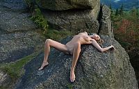 Babes: cute young blonde girl with a navel piercing posing naked on rocks in high mountains