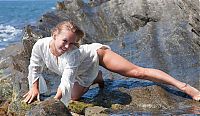 Babes: young blonde girl undresses her white blouse on the rocky shore at the sea