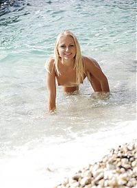 Babes: young blonde girl reveals her white fishnet knee highs in the sea on the rocky beach