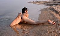 Babes: young black haired girl reveals her white blouse on the shingle beach with pebbles